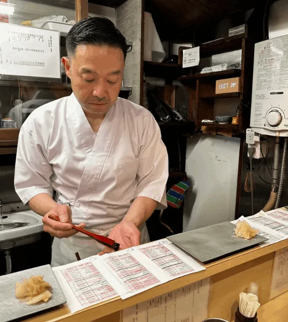 厨房で伝票を確かめる白い調理服の料理人